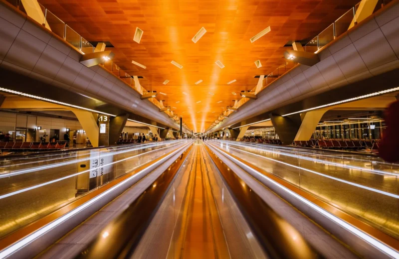 Dramatic long exposure of a modern airport terminal's moving walkalator with architectural ceiling design.