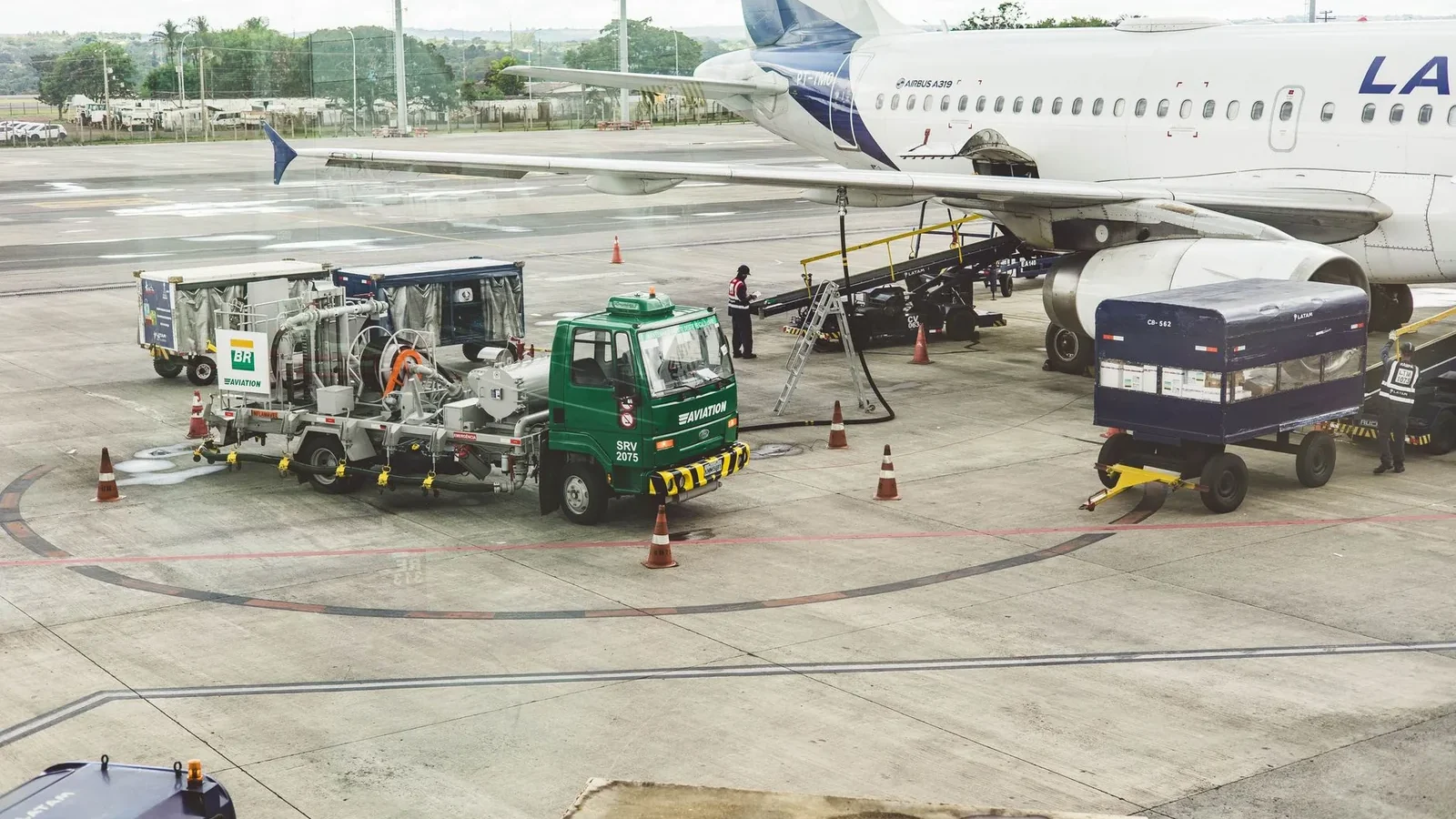 Ground support services in action at an airport terminal with visible aircraft and service vehicles.