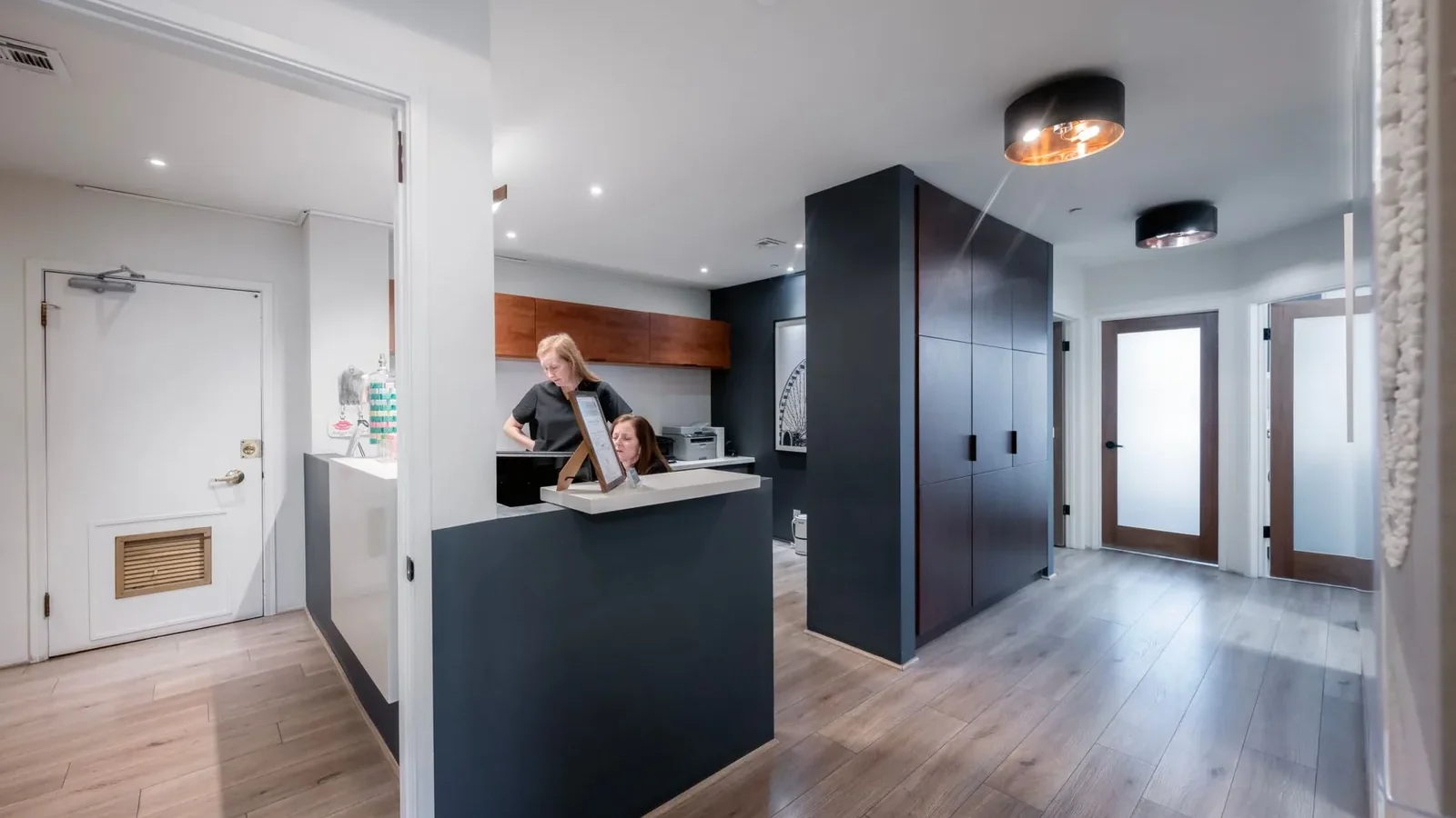 Clean and modern reception area in a Beverly Hills dental office with staff at the desk.