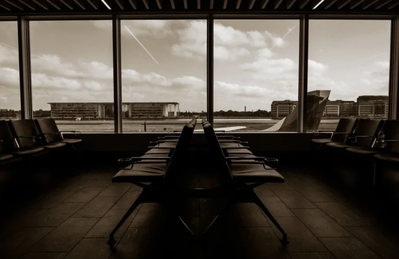 Quiet airport terminal in sepia tone overlooking runway and airplane wing.