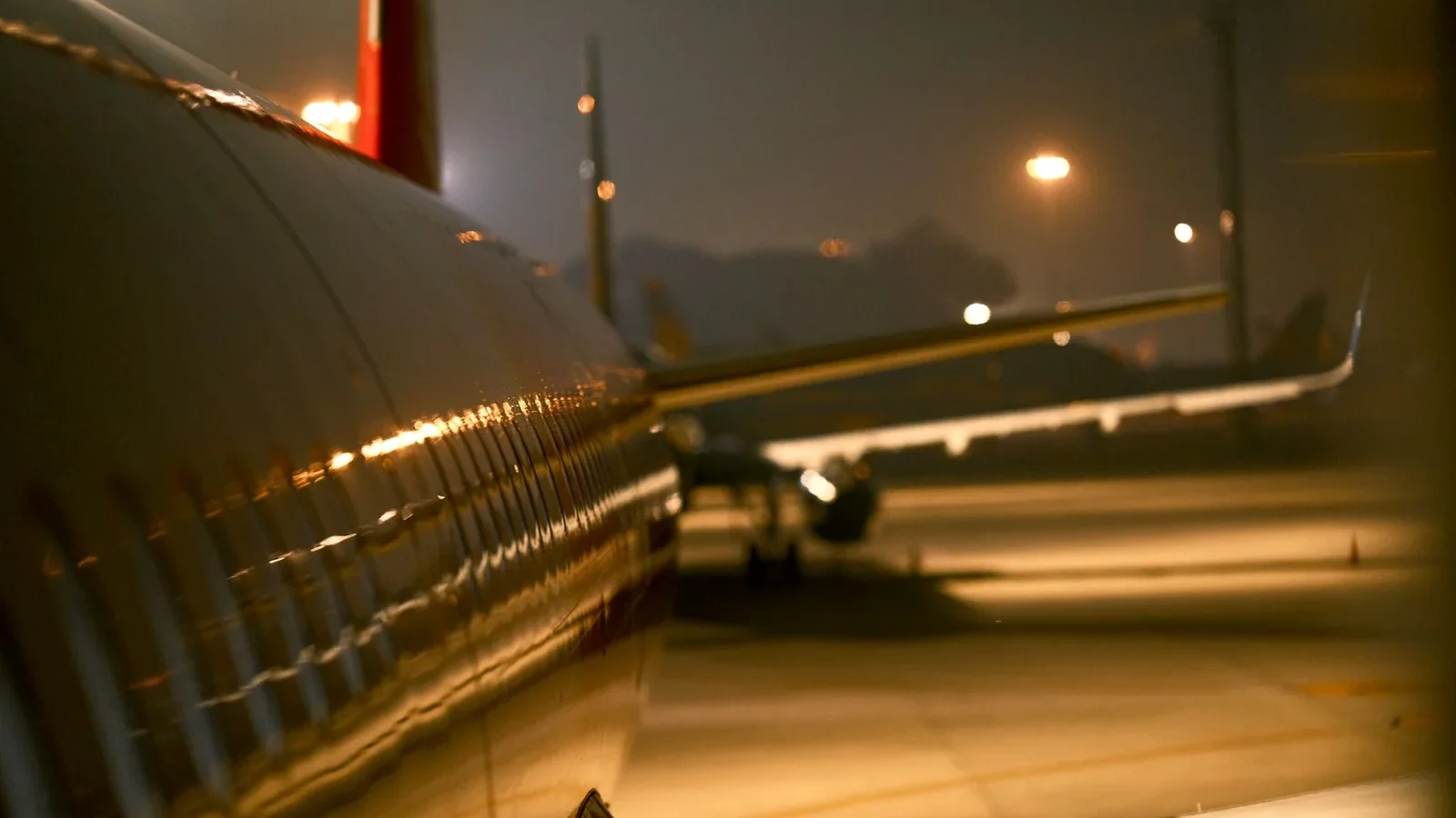 Aviation-themed night scene with airplane wings and runway lighting at Vietnam airport.