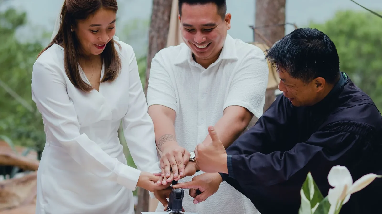 A joyful couple finalizing their wedding with the officiant outdoors.