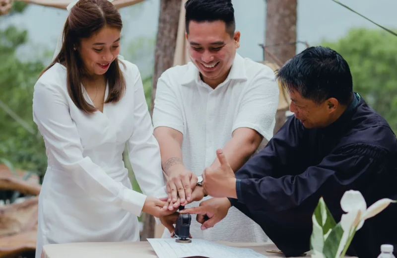 A joyful couple finalizing their wedding with the officiant outdoors.