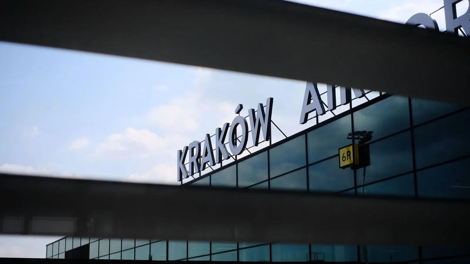 A modern architectural detail of the facade of Kraków Airport with reflective glass panels.
