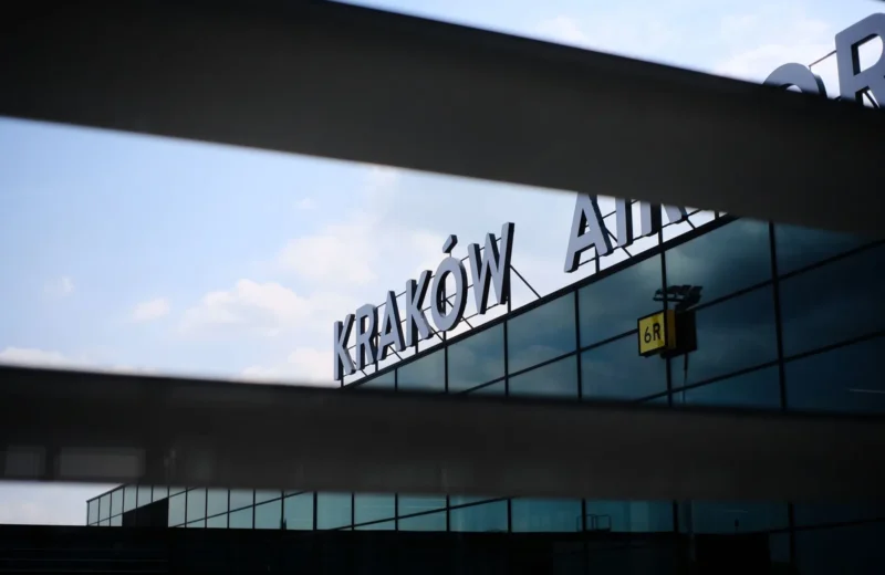 A modern architectural detail of the facade of Kraków Airport with reflective glass panels.