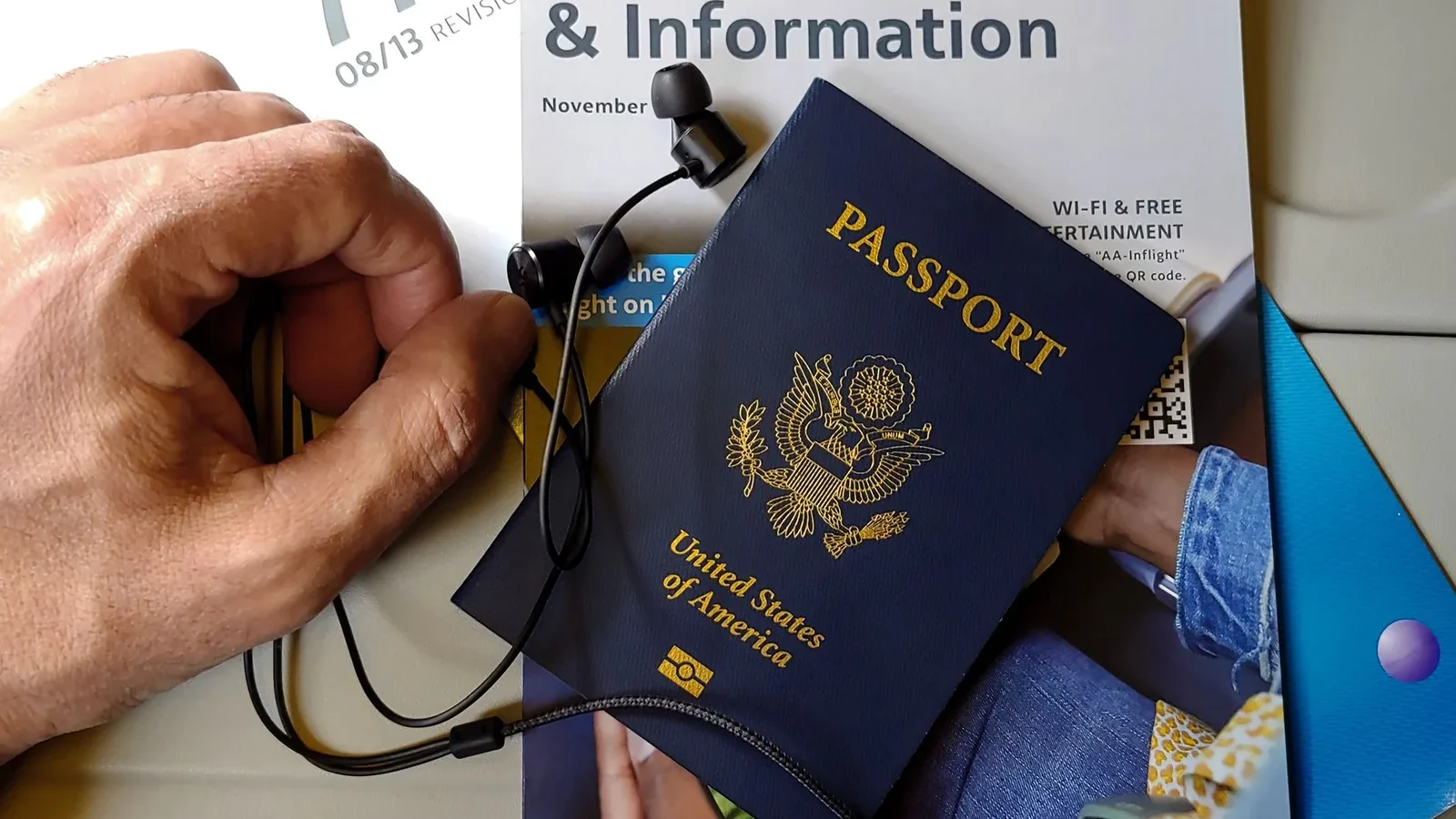 Close-up of US passport with inflight magazine and headphones on an airplane seat, ready for travel.