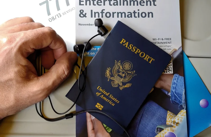 Close-up of US passport with inflight magazine and headphones on an airplane seat, ready for travel.
