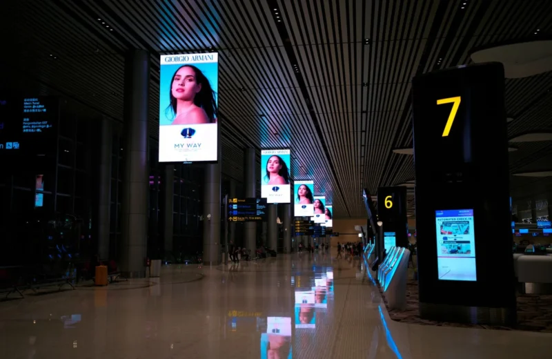 Empty airport hallway with digital displays and glossy floors at night.