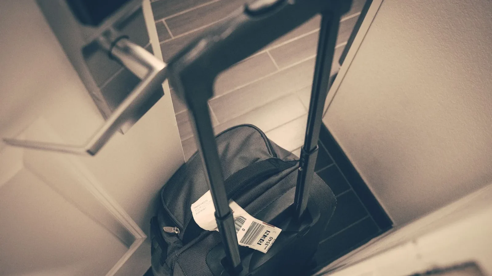 Travel suitcase with tag by hotel door, symbolizing travel or business trip.