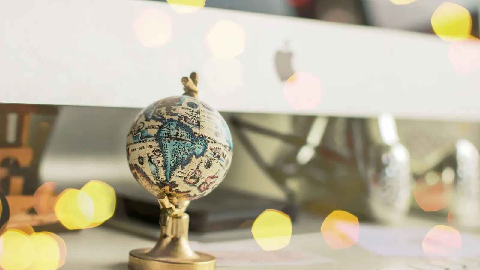 Close-up of a miniature globe on an office desk with a bokeh light effect, creating a dreamy atmosphere.