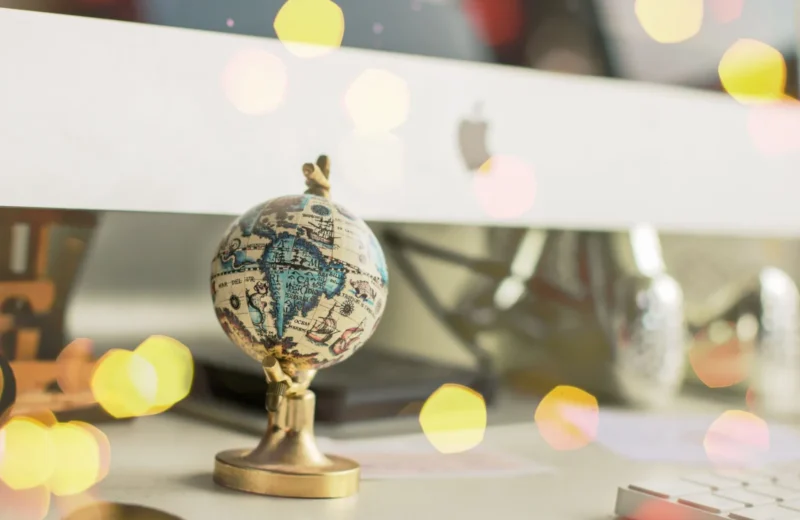Close-up of a miniature globe on an office desk with a bokeh light effect, creating a dreamy atmosphere.